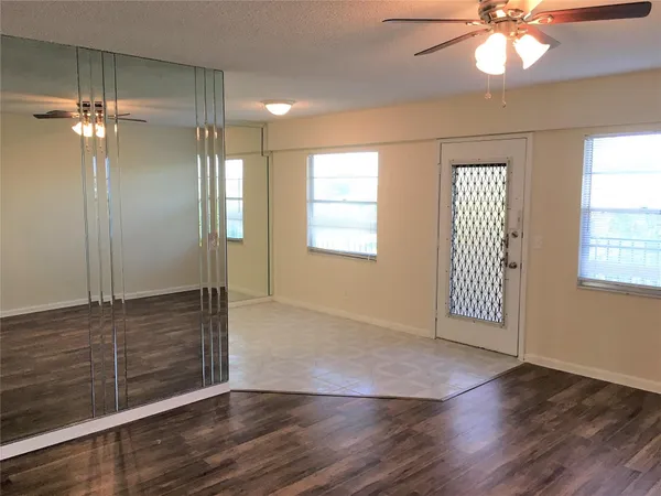 a view of an empty room with wooden floor and a window