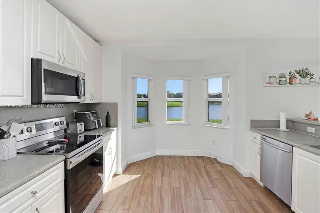 a kitchen with granite countertop a stove top oven a sink dishwasher and microwave with wooden floor