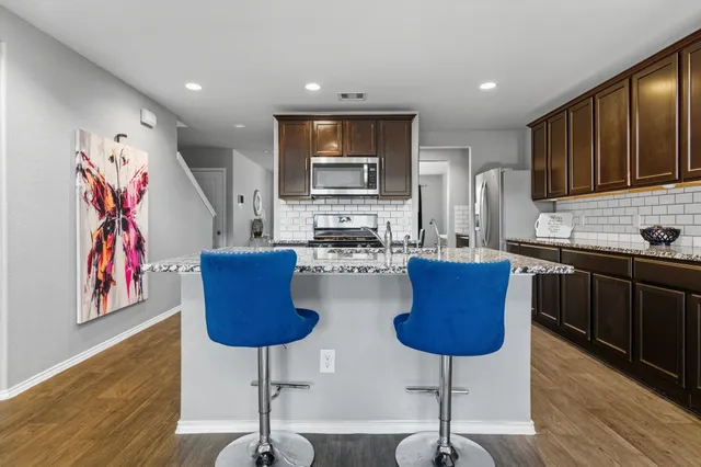 a kitchen with stainless steel appliances granite countertop a refrigerator and a stove top oven with wooden floor