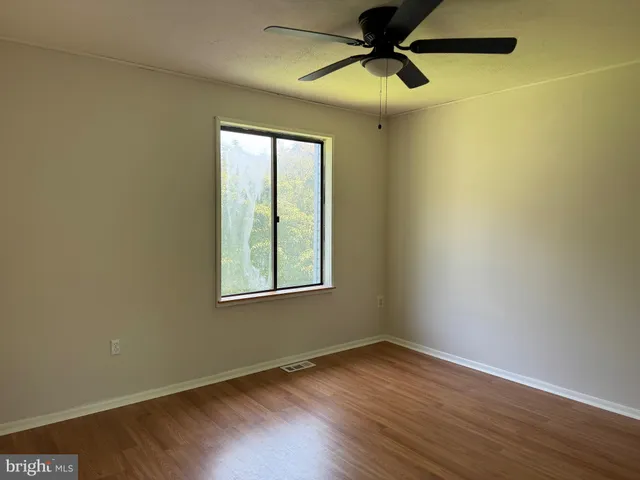 an empty room with a window and a fan