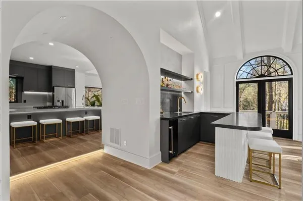 a kitchen with stainless steel appliances granite countertop a refrigerator a stove a sink a dining table and chairs with wooden floor