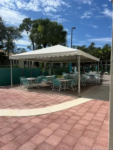 a view of a patio with table and chairs under an umbrella with a fire pit