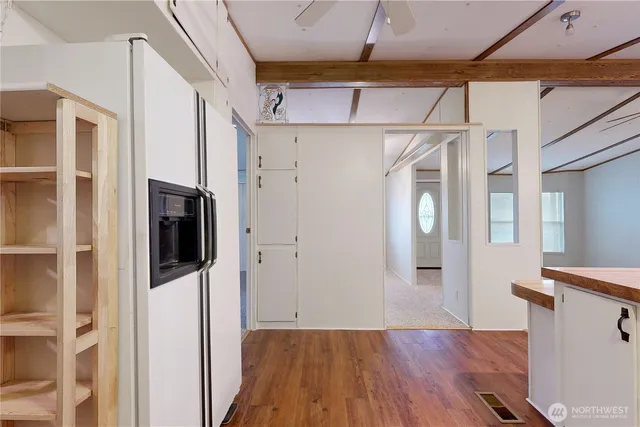 a view of a refrigerator in kitchen and an empty room