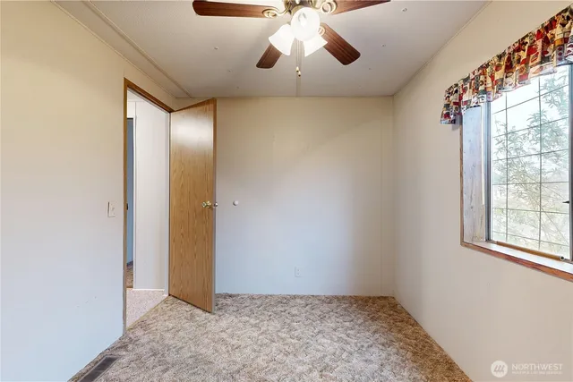 a view of an empty room with window and chandelier fan