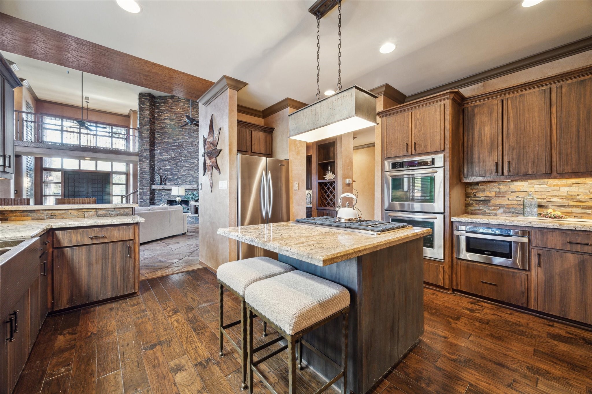 2614 Rip Van Winkle Drive Pearland, TX 77581 - Photo 12 of 31 a kitchen with stainless steel appliances granite countertop a stove a sink a microwave oven and a dining table with wooden floor