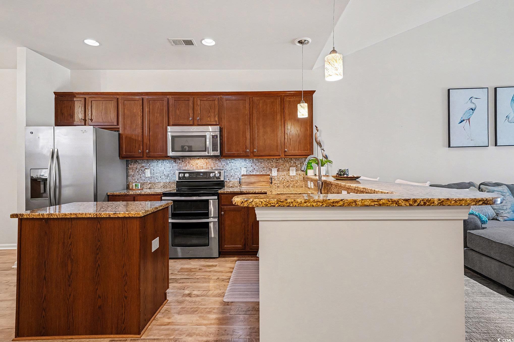 1526 Palmina Loop, Unit C Myrtle Beach, SC 29588 - Photo 6 of 34 Kitchen featuring a peninsula, appliances with stainless steel finishes, decorative light fixtures, light wood-type flooring, and light stone counters