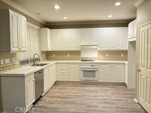 a kitchen with granite countertop white cabinets and white stainless steel appliances