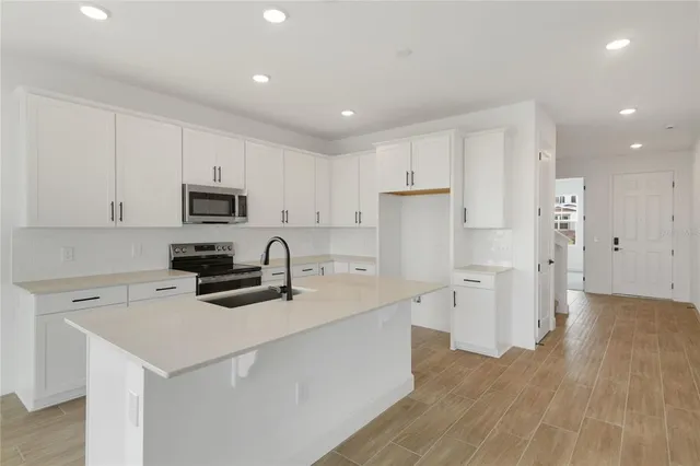 a kitchen that has a lot of white cabinets and stainless steel appliances