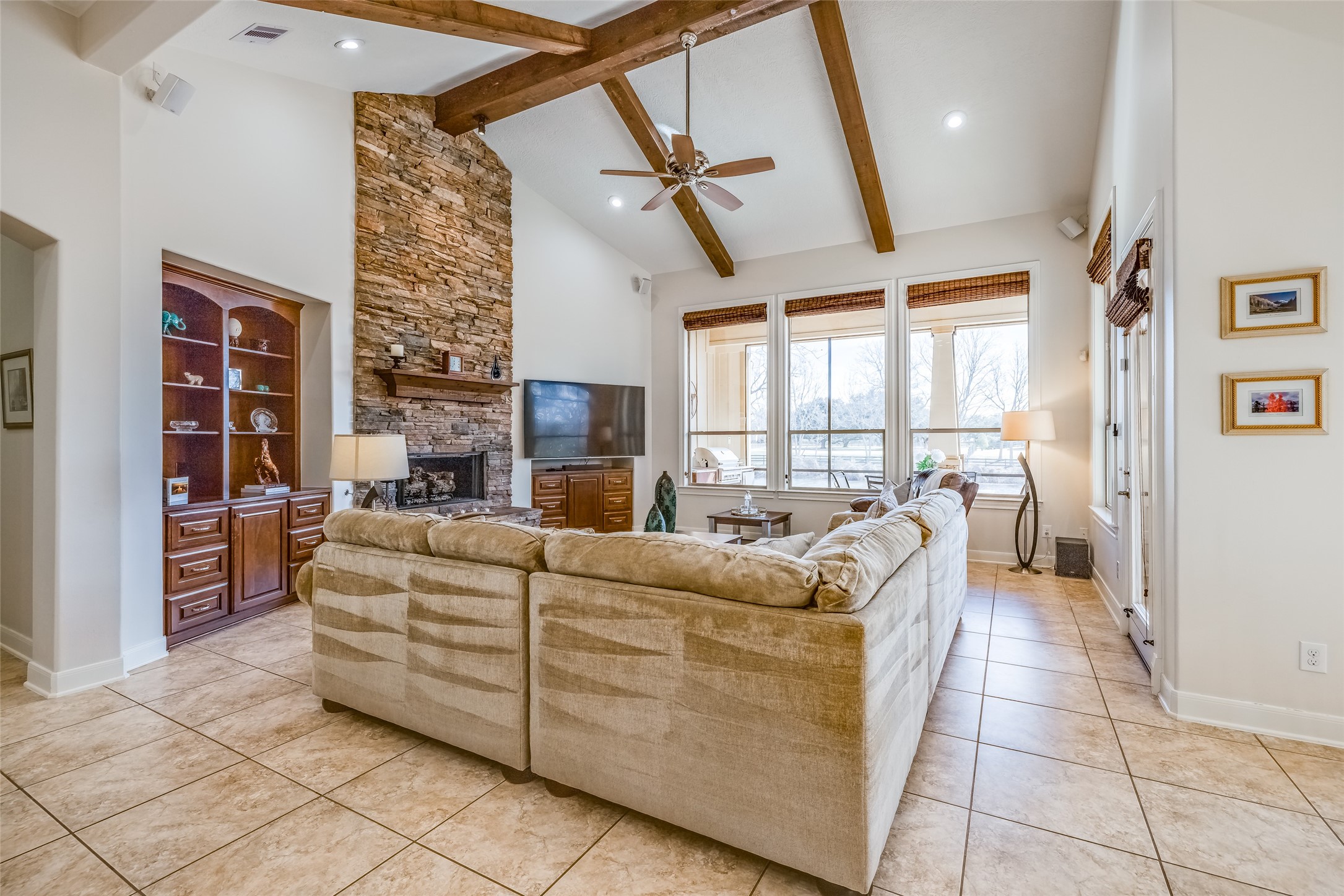 31102 Lower Oxbow Trace Fulshear, TX 77441 - Photo 16 of 50 Gorgeous large open plan Living Room with high ceilings with wooden beams, gas fire, built in shelves & storage, tiled floor, wall on windows that look out to the pool & Oxbow Lake