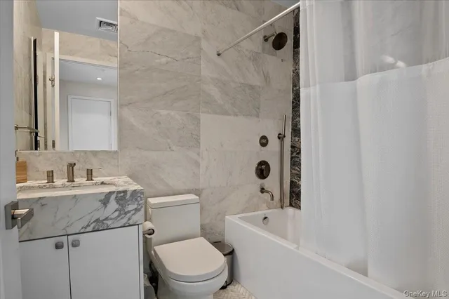 a bathroom with a granite countertop sink a toilet and shower