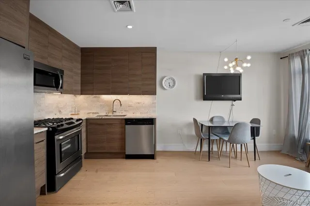 a kitchen with stainless steel appliances granite countertop a stove top oven a sink a dining table and chairs