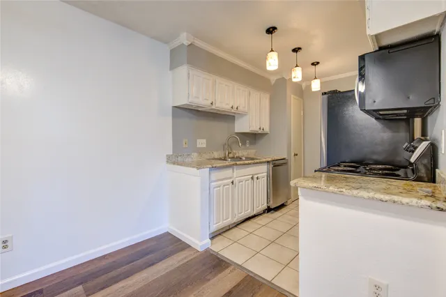 an empty room with wooden floor chandelier fan and windows