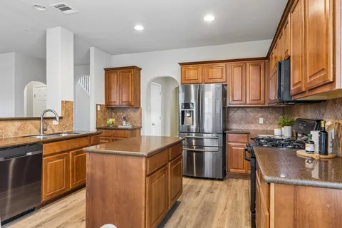 a kitchen with stainless steel appliances granite countertop a refrigerator a sink and a stove