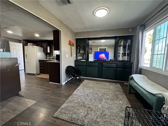 a living room with stainless steel appliances furniture a rug and a flat screen tv