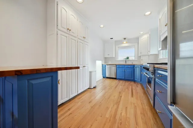 a kitchen with granite countertop wooden floors wooden cabinets and stainless steel appliances
