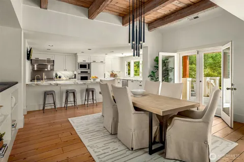 a dining room with stainless steel appliances granite countertop a table chairs and a view of kitchen