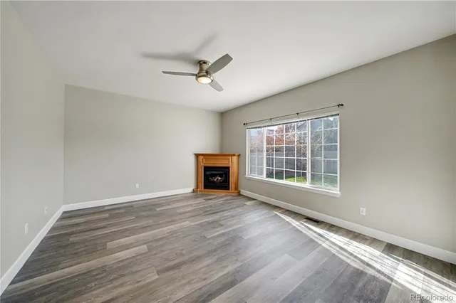 a view of an empty room with a window and wooden floor