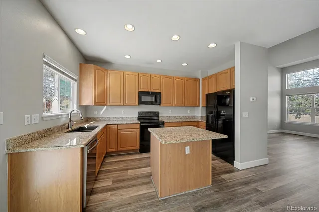 a kitchen with stainless steel appliances granite countertop a stove top oven a refrigerator a sink and dishwasher with wooden floor