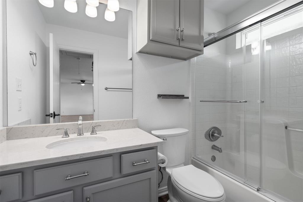 13132 Highway 78 Blue Ridge, TX 75424 - Photo 19 of 35 Bathroom featuring a vanity with a white countertop and undermount sink, gray cabinetry with modern hardware, a large wall-mounted mirror, and a shower-tub combination with sliding glass doors
