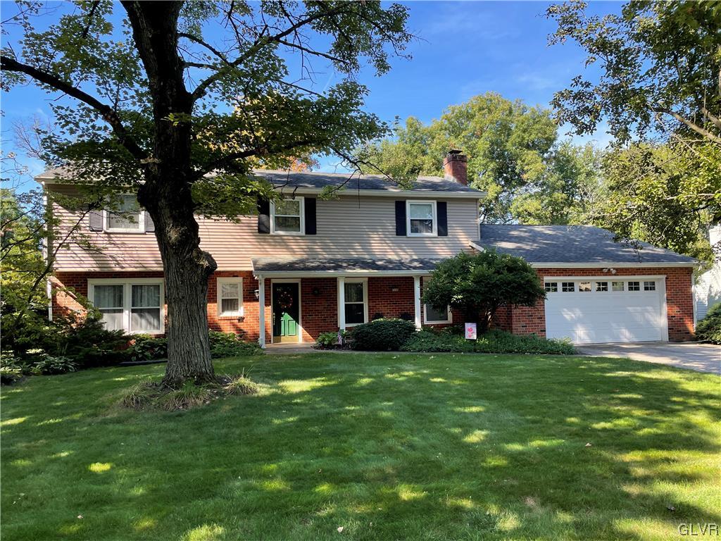 a view of a brick house with a big yard and large trees