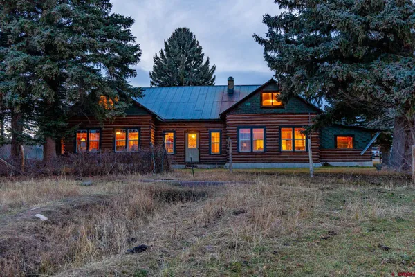 a front view of a house with large trees