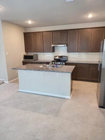 a kitchen with stainless steel appliances a sink a stove a microwave a sink a refrigerator and cabinets