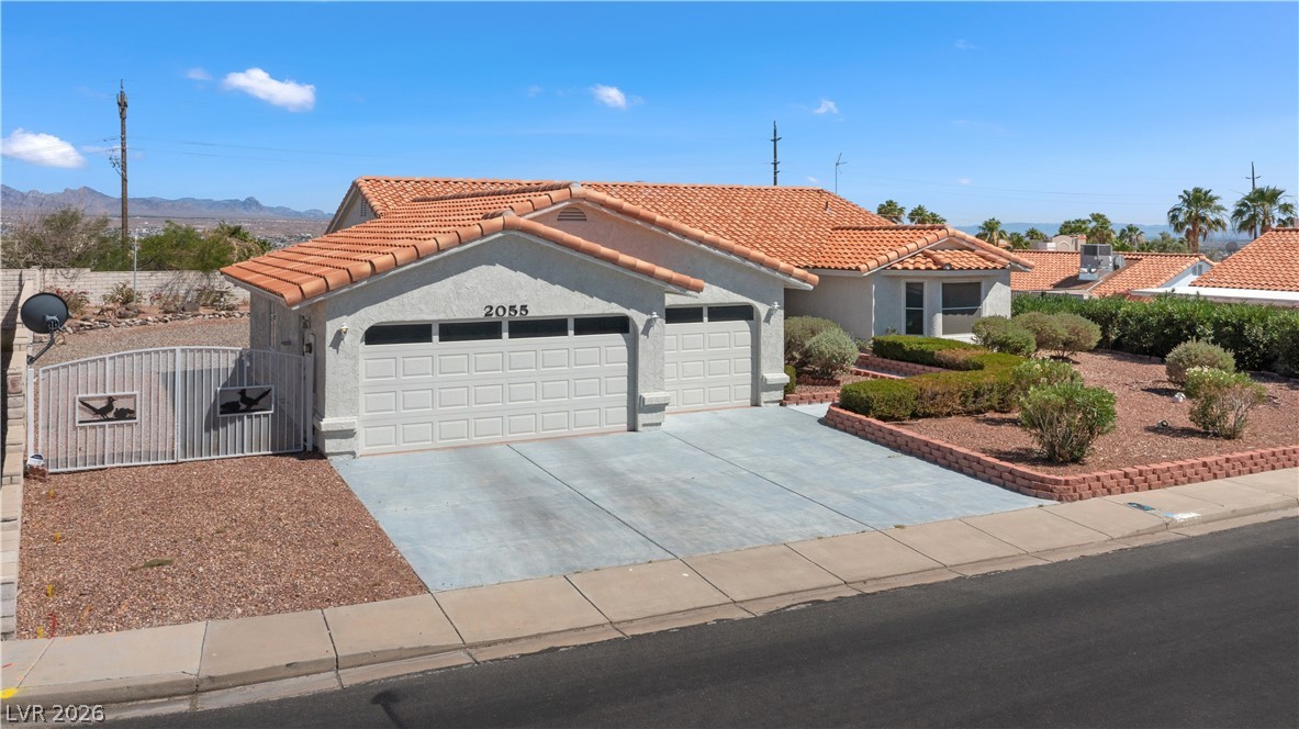 2055 Cholla Way Laughlin, NV 89029 - Photo 67 of 87 A well-maintained desert landscape frames this welcoming residence, featuring a two-car garage and distinctive tiled roof.