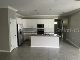a view of kitchen with stainless steel appliances granite countertop a refrigerator and a stove top oven
