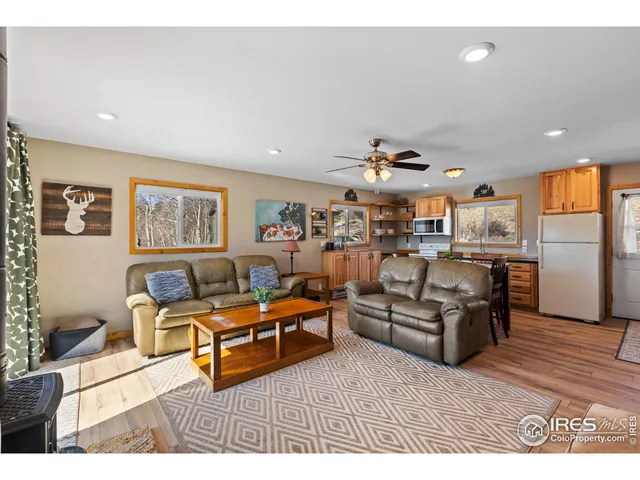 a living room with furniture kitchen view and a wooden floor