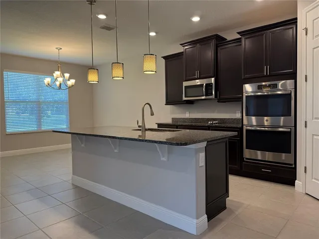 a kitchen with kitchen island granite countertop a stove a sink and a microwave