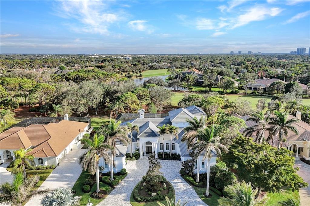 253 Cheshire Way Naples, FL 34110 - Photo 4 of 50 Aerial perspective of suburban area with a nearby body of water and a tree filled landscape
