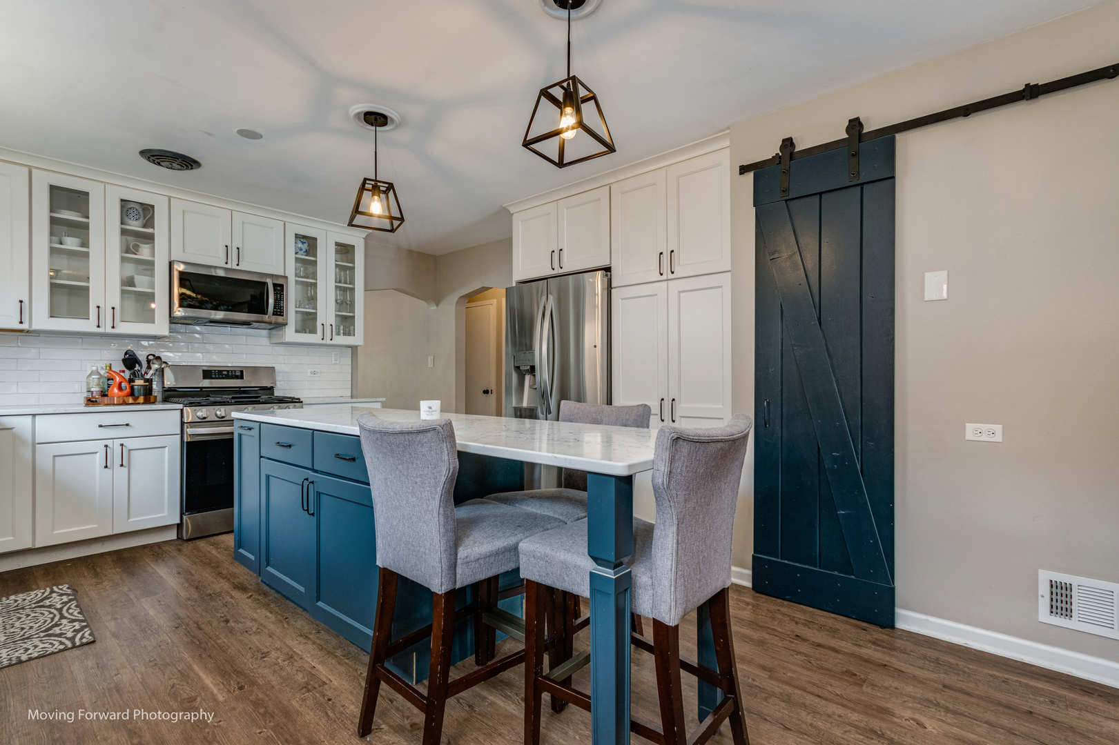 7023 29th Place Berwyn, IL 60402 - Photo 7 of 36 a kitchen with stainless steel appliances granite countertop a table chairs refrigerator and microwave