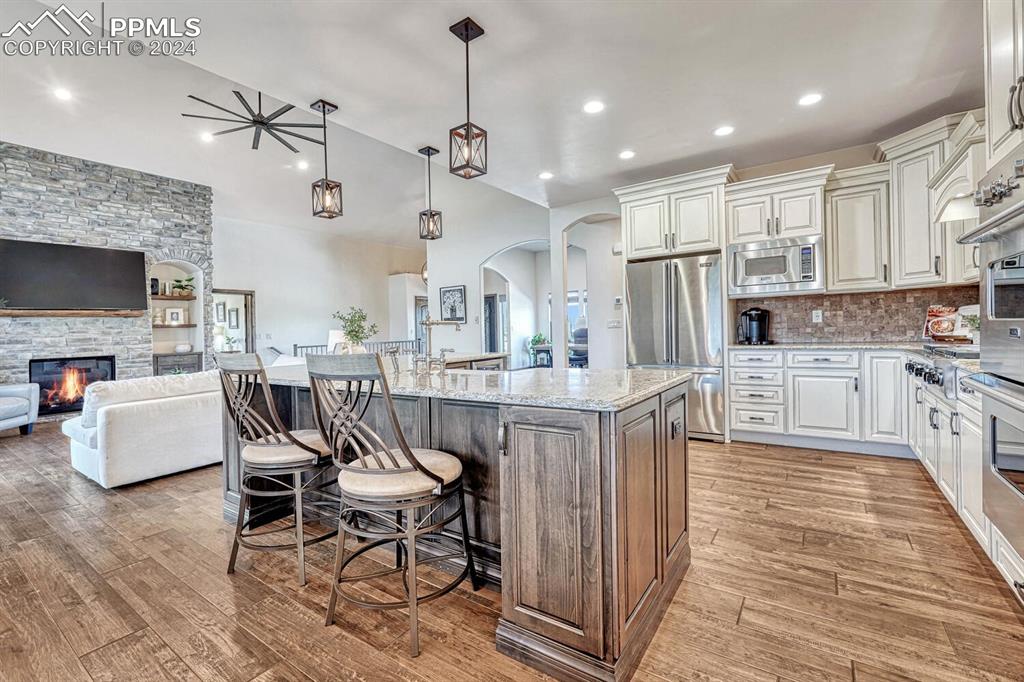 19210 Royal Troon Drive Monument, CO 80132 - Photo 12 of 50 a kitchen with stainless steel appliances kitchen island granite countertop a dining table chairs refrigerator and sink