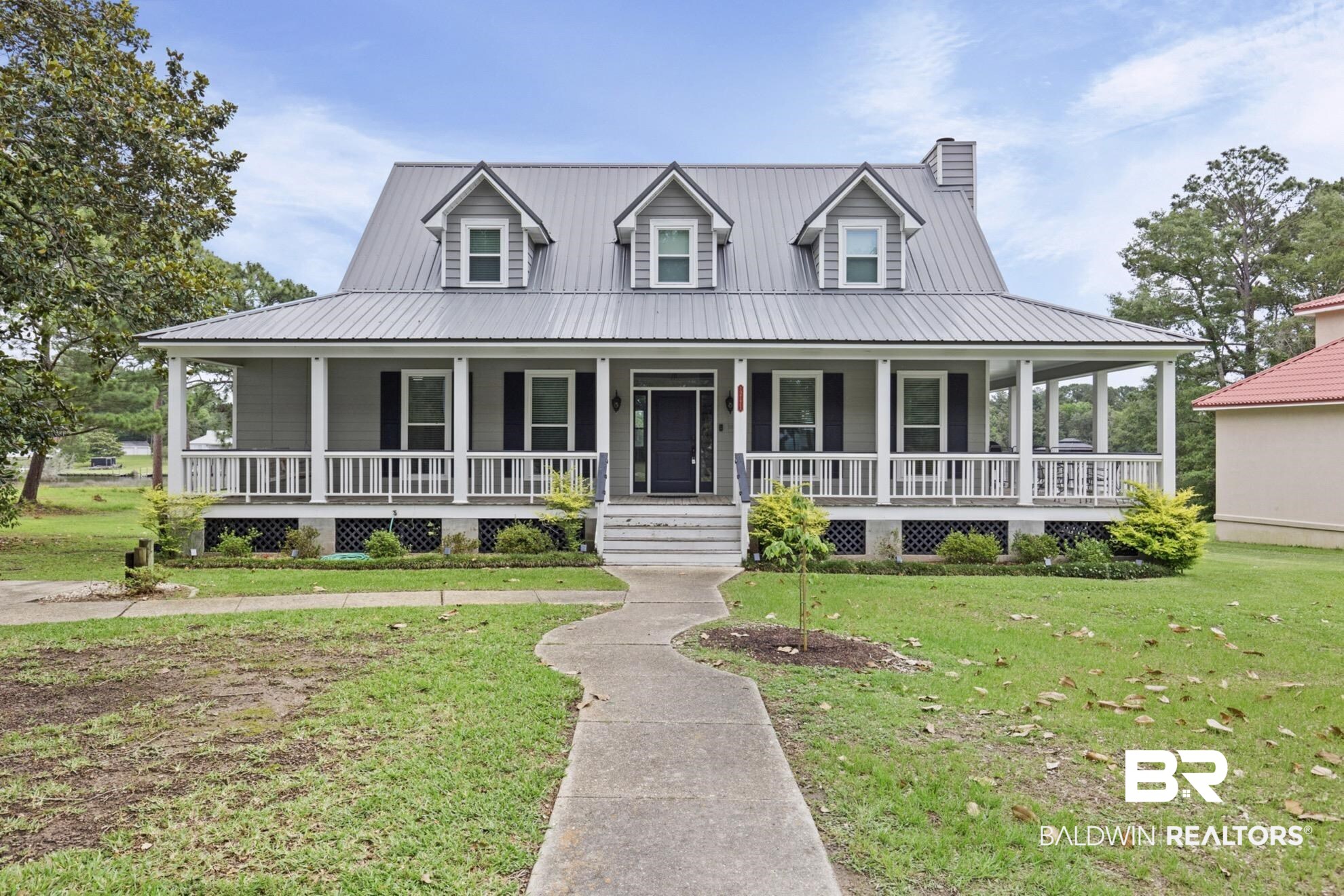12171 Marguerite Drive Coden, AL 36523 - Photo 1 of 44 Exterior featuring a wide covered porch with white railing, gray siding, a metal roof, and three dormer windows