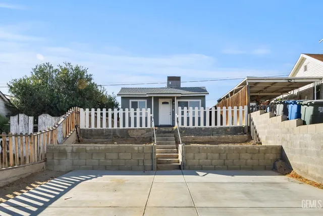 a view of a house with a small yard and wooden fence