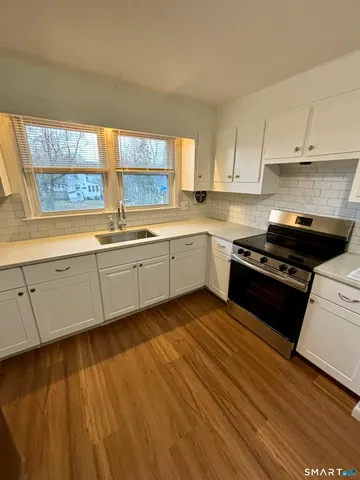 a kitchen with sink a stove and white cabinets