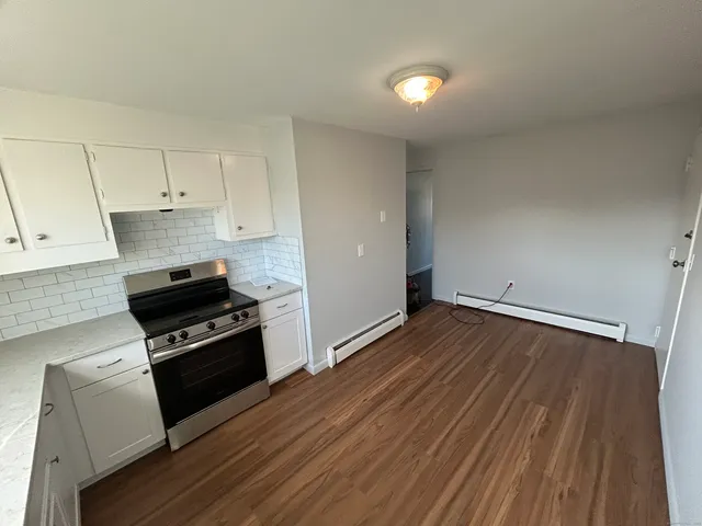a kitchen with granite countertop wooden floors appliances and cabinets