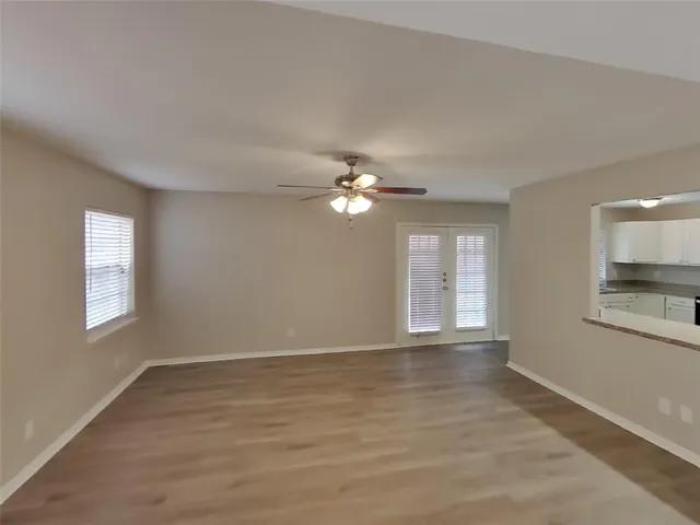 a view of empty room with wooden floor and fan