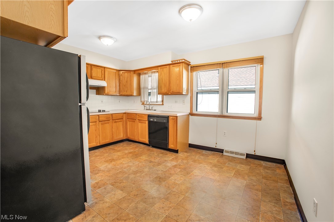 1590 Norledge Road Akron, OH 44305 - Photo 11 of 21 Kitchen with sink, refrigerator, tasteful backsplash, black dishwasher, and light tile floors