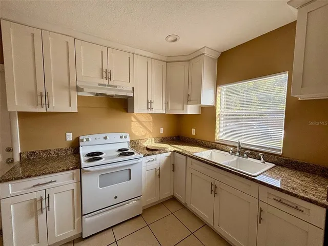 a kitchen with granite countertop white cabinets and white appliances