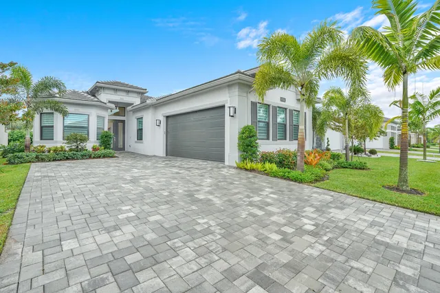 a front view of a house with a garden and palm trees