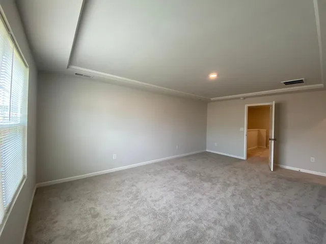 an empty room with a window and kitchen view
