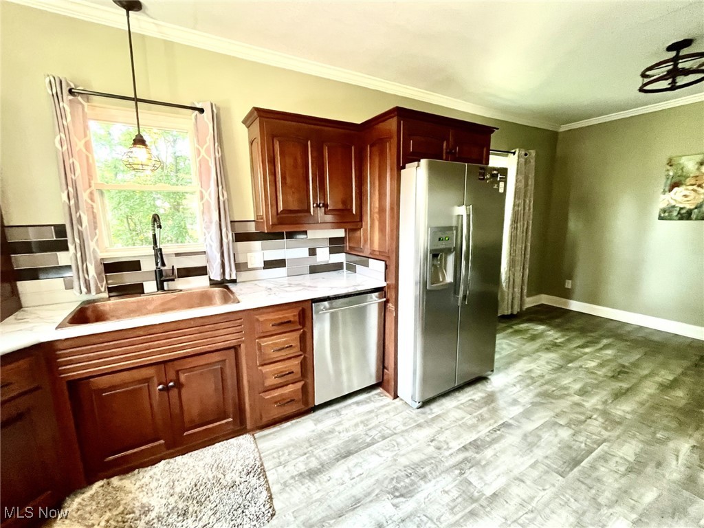4440 Dryden Court Southwest Canton, OH 44708 - Photo 12 of 28 Kitchen featuring appliances with stainless steel finishes, light wood-style floors, ornamental molding, light stone counters, and pendant lighting