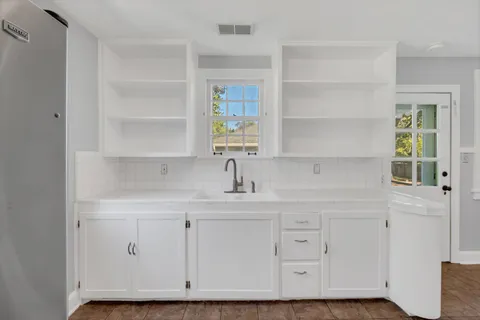 a kitchen with white cabinets and a window