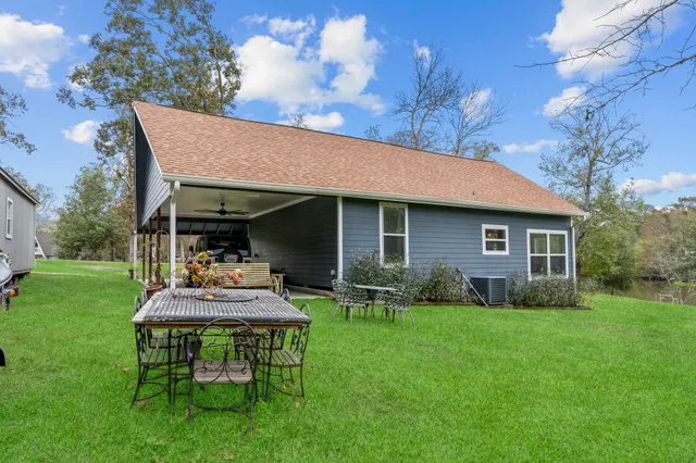 a view of a house with table and chairs in a yard
