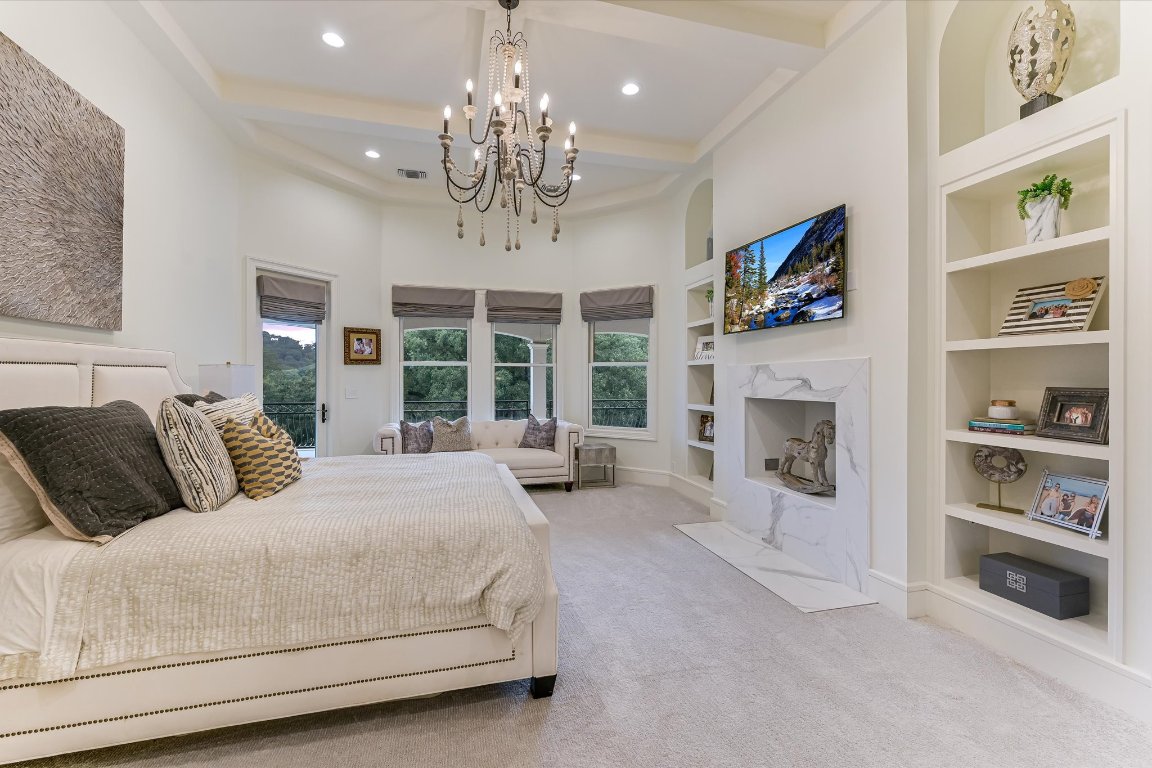 14132 Flat Top Ranch Road Austin, TX 78732 - Photo 27 of 40 a spacious bedroom with a large bed and a fireplace