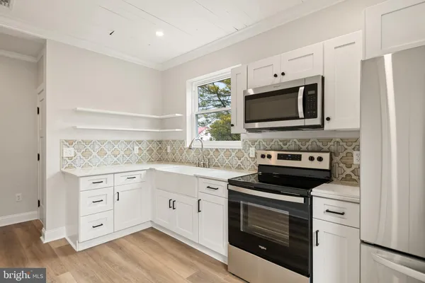 a kitchen with cabinets stainless steel appliances and wooden floor