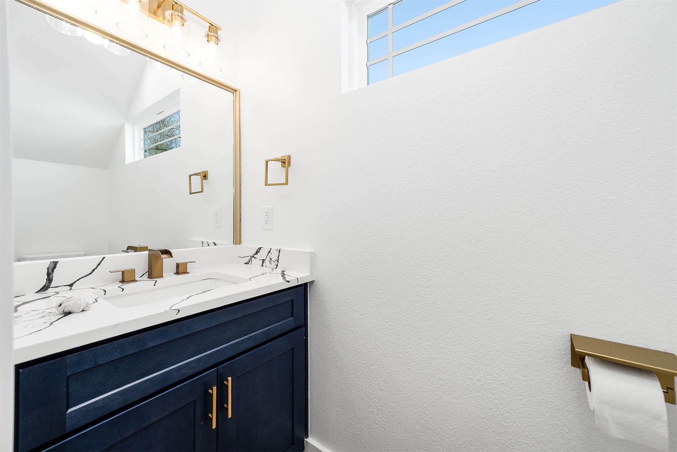 8602 Hoffman Street Houston, TX 77016 - Photo 14 of 30 Stylish half bath featuring a quartz vanity, ash blue cabinetry, and elegant gold fixtures.