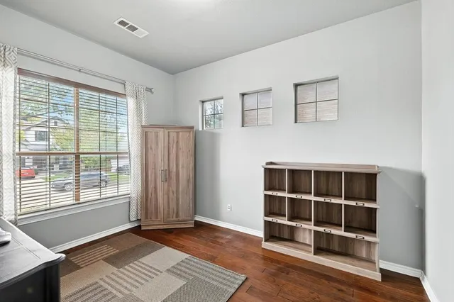 a view of an empty room with wooden floor and windows