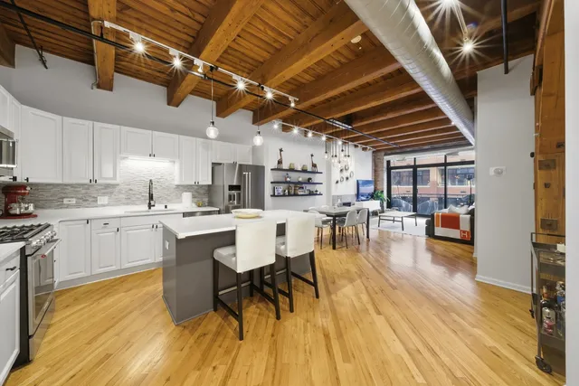 a kitchen with a sink a counter space dining table and stainless steel appliances